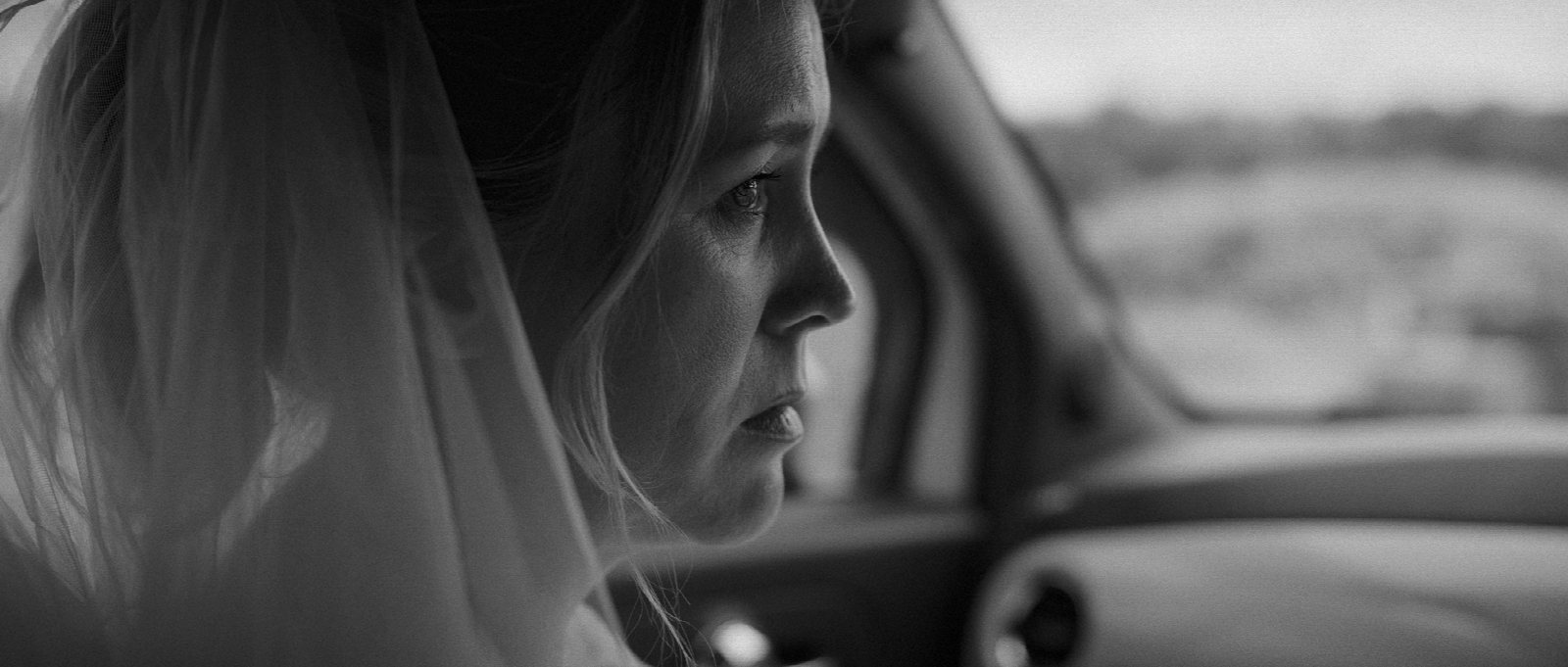 Actor in a wedding dress on the side of a road holding a MARRY ME sign